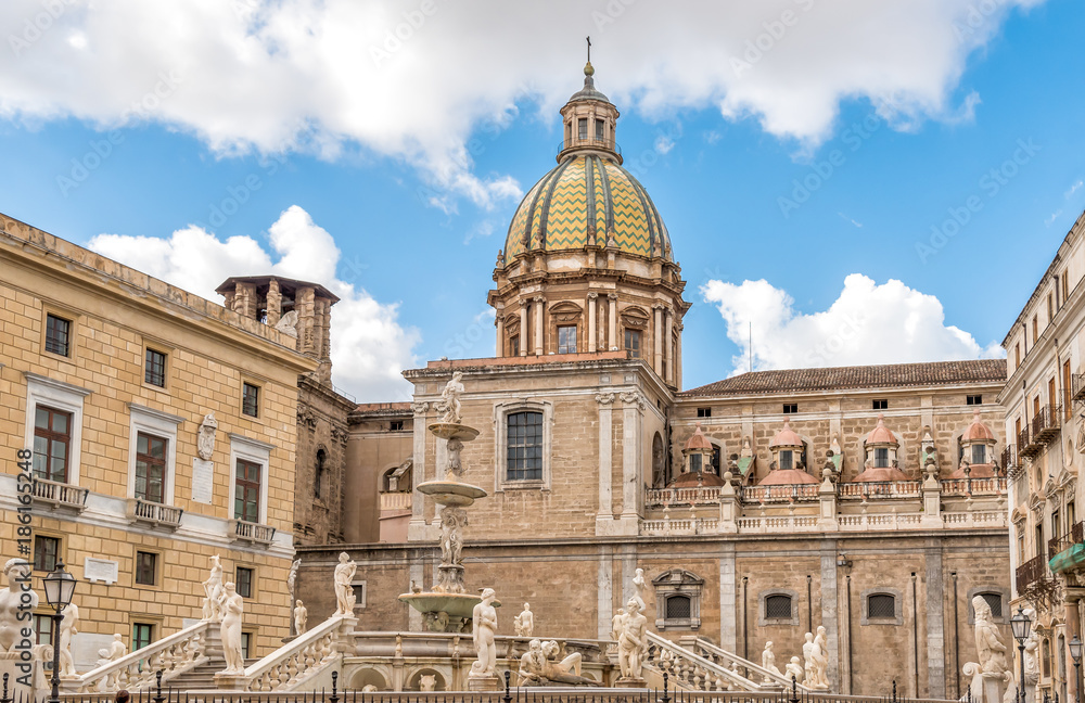View of San Giuseppe dei Teatini church dome with statues of the Pretoria fountain ahead in Palermo, Sicily, Italy