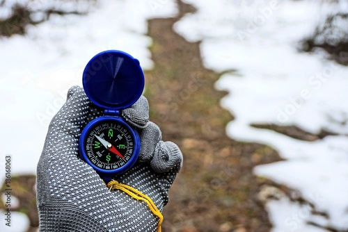 компас в руке на фоне тропинки в зимнем лесу