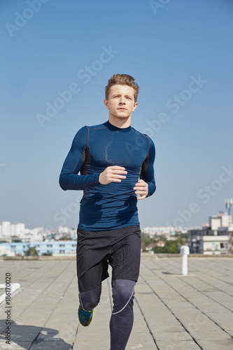 Male model in sportfit run opposite blue sky