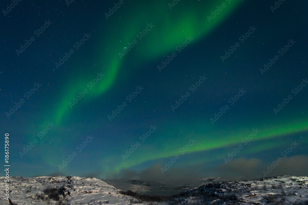 Northern lights, aurora over hills and tundra in the winter.