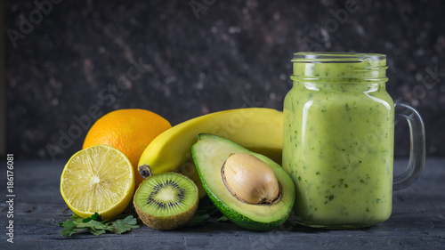 Smoothie of avocado, banana, kiwi and lemon on a wooden table against a black wall. Vegetarian food for a healthy lifestyle.