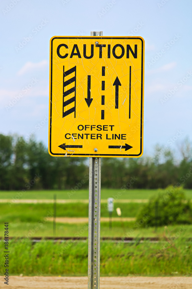 A caution offset center line road sign