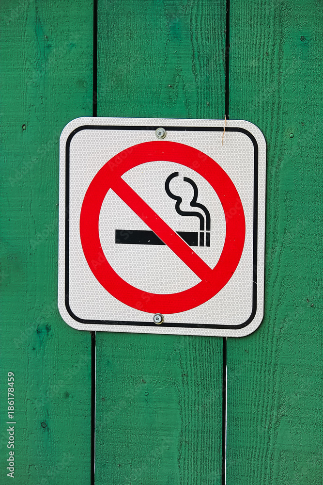 No smoking sign on a green wooden background No smoking sign on a green wooden background