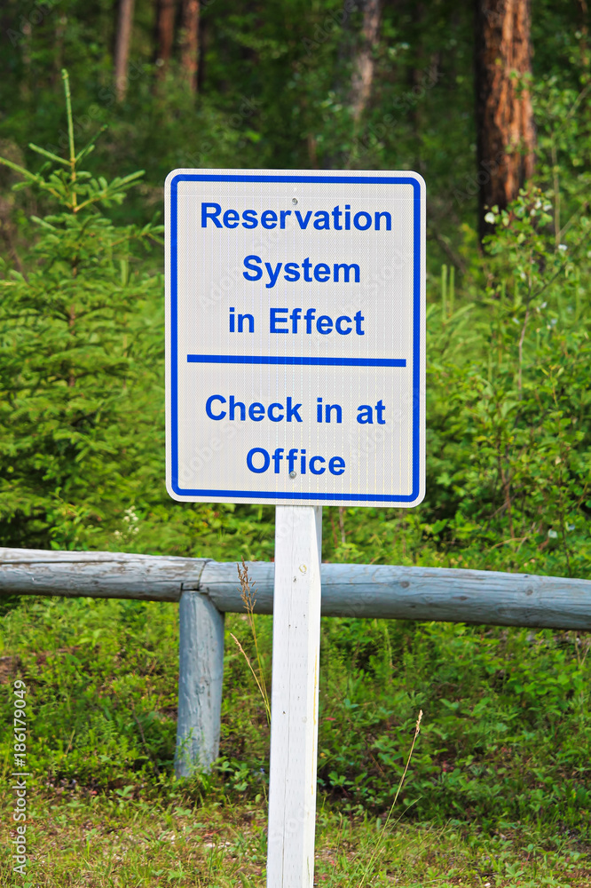 A reservation system in effect sign, check in at office