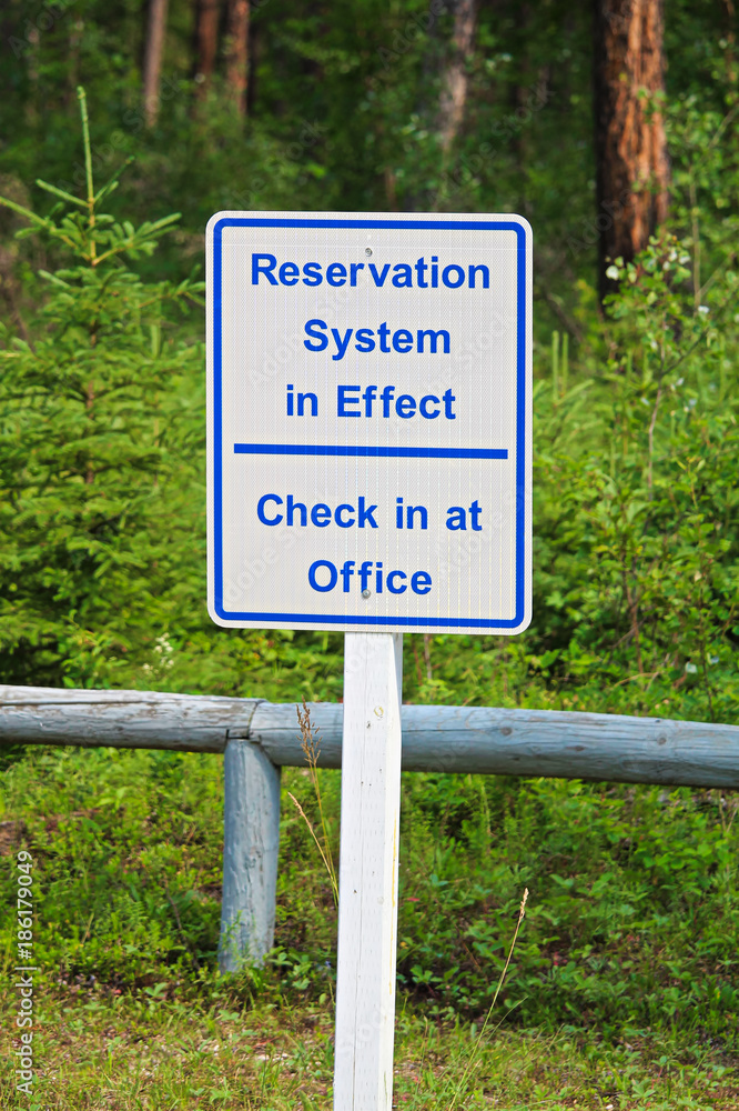 A reservation system in effect sign, check in at office A reservation system in effect sign, check in at office