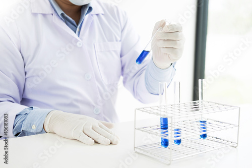 Asian scientific researcher working in laboratory holds test tube in hand a liquid solution analysis using chemical manufacturing.