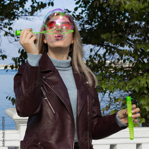 Young pretty girl blows soap bubbles, outdoor  