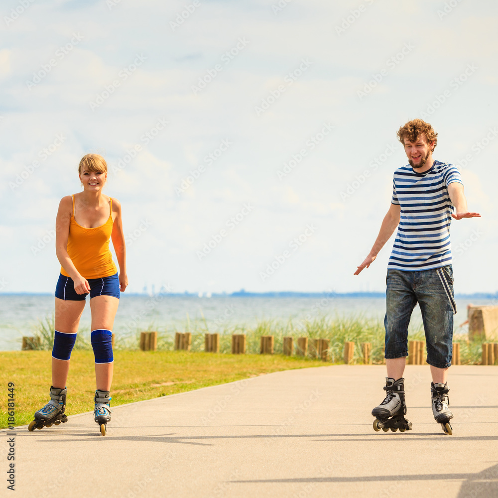 Fototapeta premium Young couple on roller skates riding outdoors
