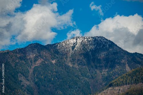 clouds on the blue sky above snow covered peak of the mountain