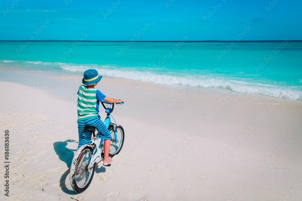 Fototapeta premium little boy riding bike on tropical beach