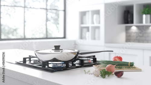 The new frying pan on the mirror cooking plate in the white interior. Fresh vegetables lie near a frying pan on a white stone table. Big window on the background.