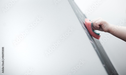 Little cute little girl paints with chalk on a blackboard at home, plays and wipes with a rag photo