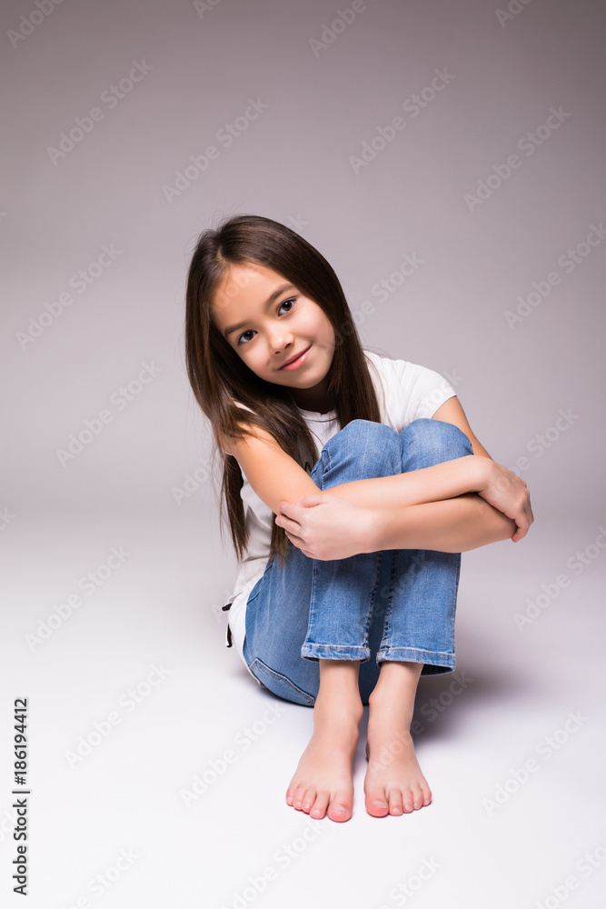 Pretty little girl sitting on the floor isolated over white background Pretty little girl sitting on the floor isolated over white background