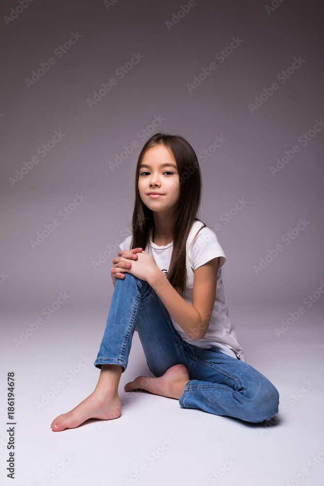 Cute little girl sitting and smiling, isolated on white with shadow on ...