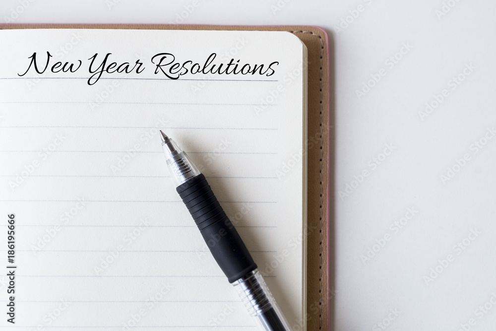 Conceptual,notebook on a white table. open diary and pen with new year resolutions words Conceptual,notebook on a white table. open diary and pen with new year resolutions words
