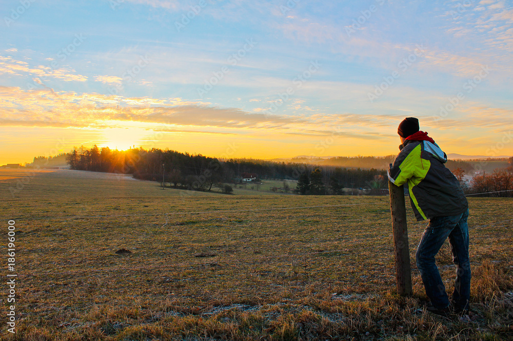 Young man in jacket looking to famous witer sunrise on Czech countryside Young man in jacket looking to famous witer sunrise on Czech countryside