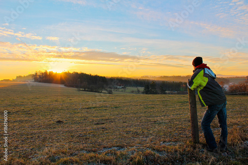 Young man in jacket looking to famous witer sunrise on Czech countryside