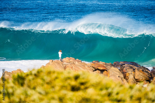Young man standing on rocks watching large crashing waves in Yallingup between the towns of Margaret River and Dunsborough in the south west of Western Australia. photo