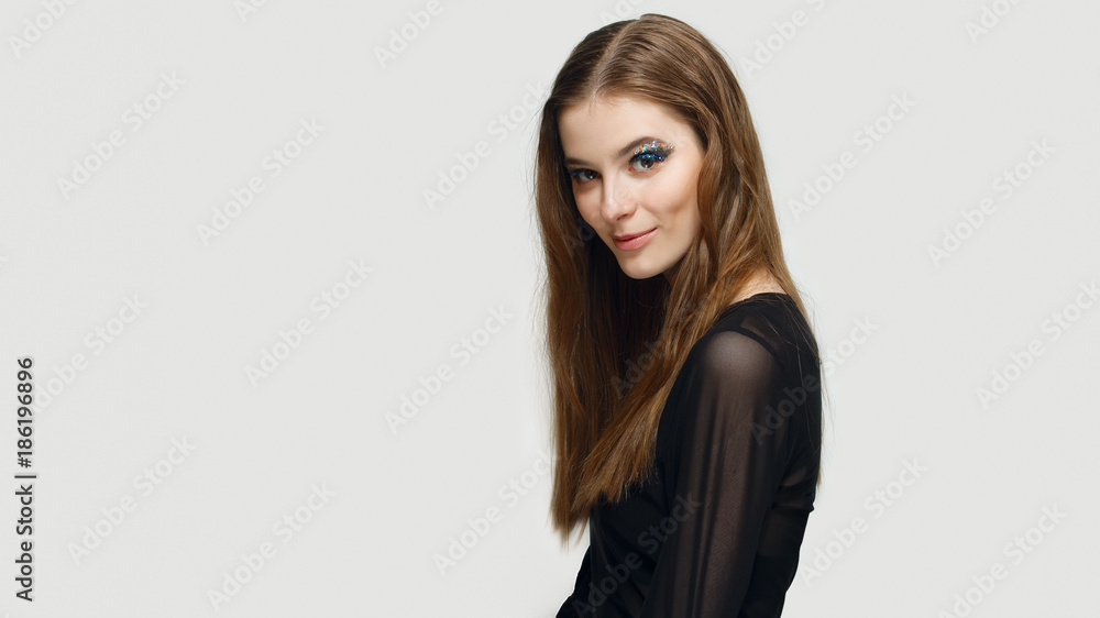 Pretty girl with creative makeup sparkles on the eyes. Girl standing half turned in profile. Pretty girl with creative makeup sparkles on the eyes. Girl standing half turned in profile.
