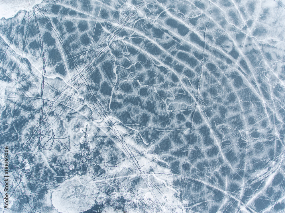 Obraz premium Flight over frozen lake breaking ice in rural village, Lithuania. Aerial photography during winter season.