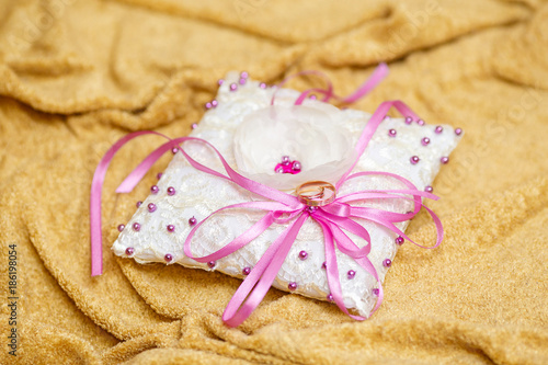 Golden wedding rings on decorated little white pillow