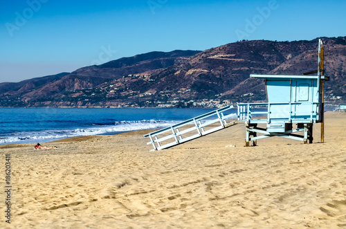 Scenic view of Malibu beach with lifeguard tower and a sunbathing woman