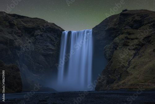 Skogafoss waterfall under the aurora glow at night
