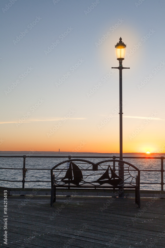 Iron Bench and Lamp-post at the end of the pier at sunset