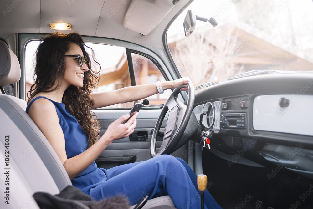Naklejka premium Beautiful young woman using her mobile phone in the car.