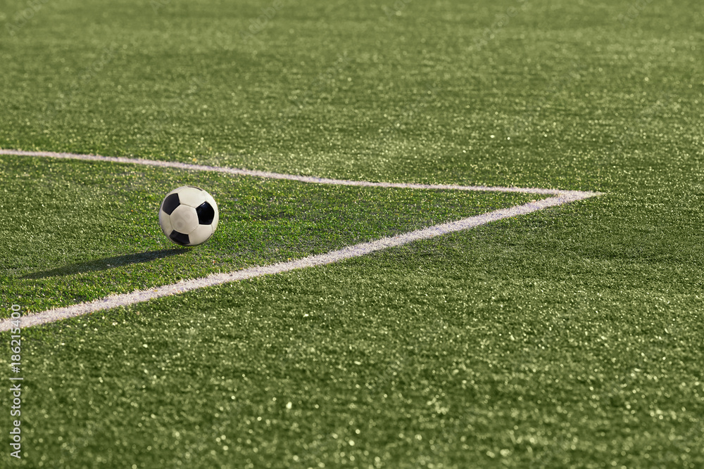 A soccer ball in near the corner marking.