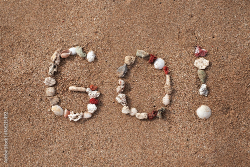 Text Go on sandy beach made from shells. Concept of travel and active lifestyle photo