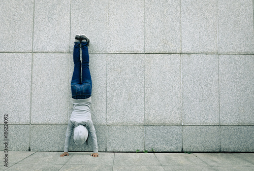 Photography female hipster doing a handstand against wall