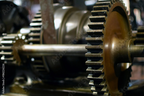 Cogwheels and axel in old mechanical system. Close up horizontal industrial image.