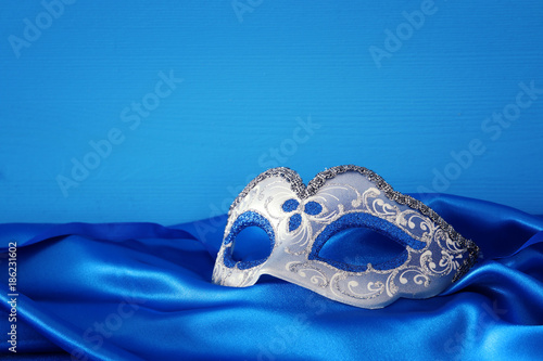 Image of elegant blue and gold venetian mask over blue silk fabric background.