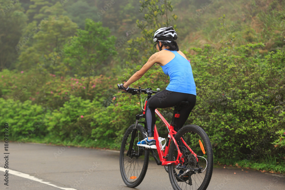 Obraz premium Young woman cyclist riding mountain bike on trail