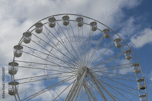 Part of a white ferris wheel on a blue sky with clouds
