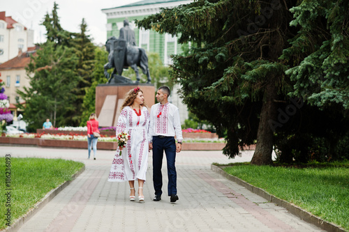 Lovely wedding couple in ukrainian traditional embroidered clothing walk with a bouquet in an old town. © AS Photo Family