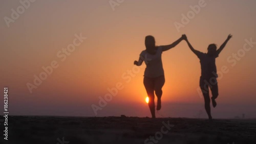 Wallpaper Mural Happy girls running at the beach on sunset in slow motion. Beauty and joyful teenager friends having fun, dancing, spraying. Beach party. Sun flare. 1920x1080 Torontodigital.ca
