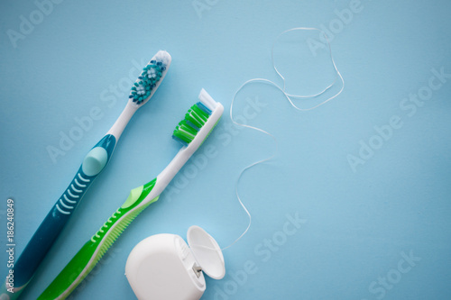 Two toothbrushes and dental floss on blue background