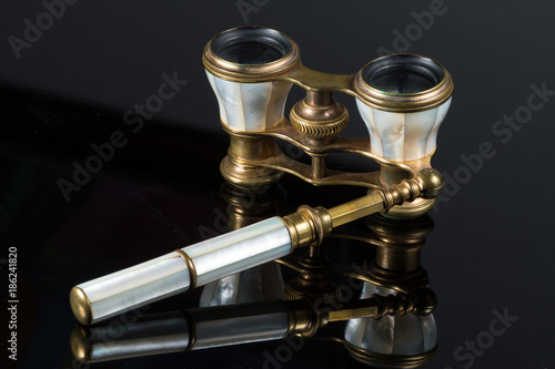 Old antique opera glasses lying on black reflective surface