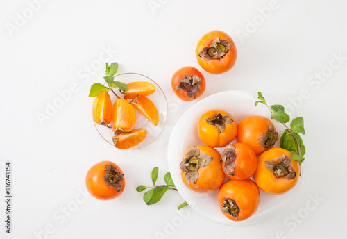 Chopped ripe persimmon in bowl on white table