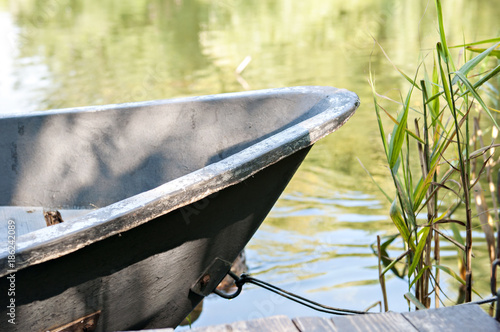 The boat is tied to a pristane on a quiet lake where wild ducks live photo