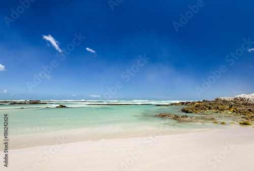 Beach view with white sand, rocks and crystal clear water at Brandfontein - Rietfontein Nature Reserve near Cape Agulhas, Western Cape Province, South Africa.