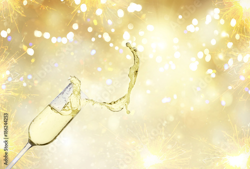 festive champagne glass with splash on golden bokeh background with lights