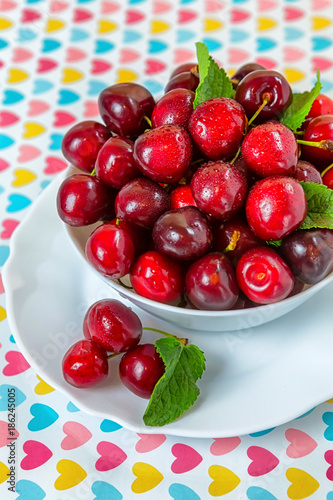 Cherries in a white plate on the table.
