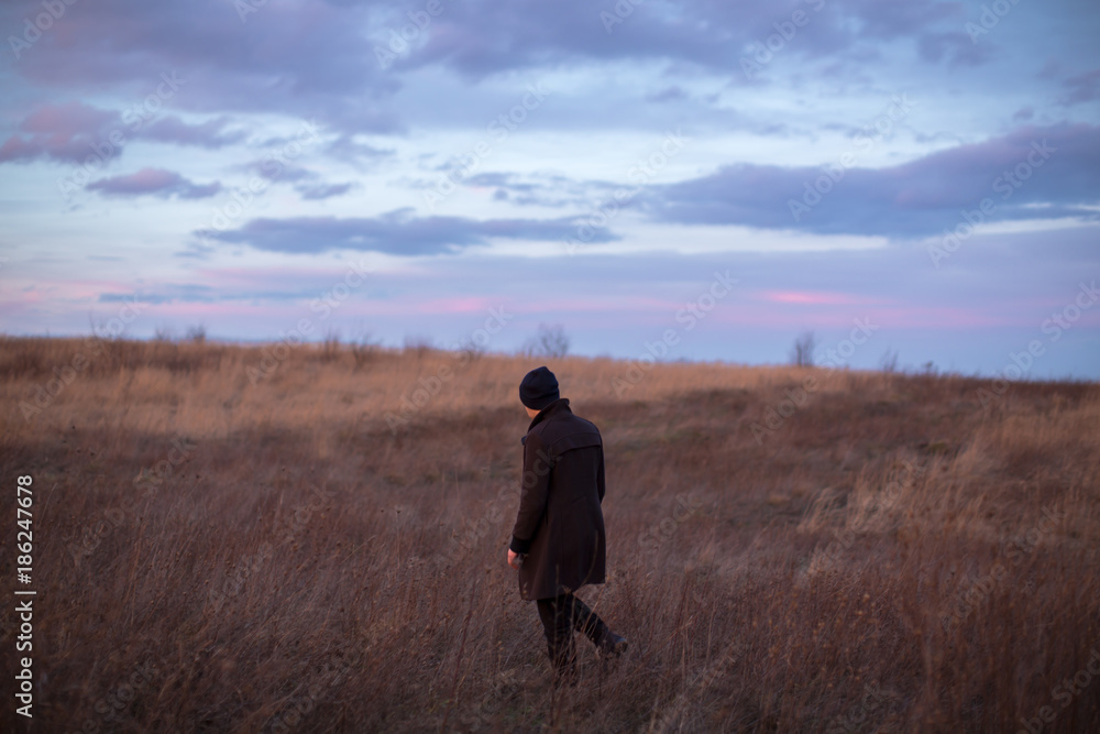 Man walking in the autumn field during sunset Man walking in the autumn field during sunset