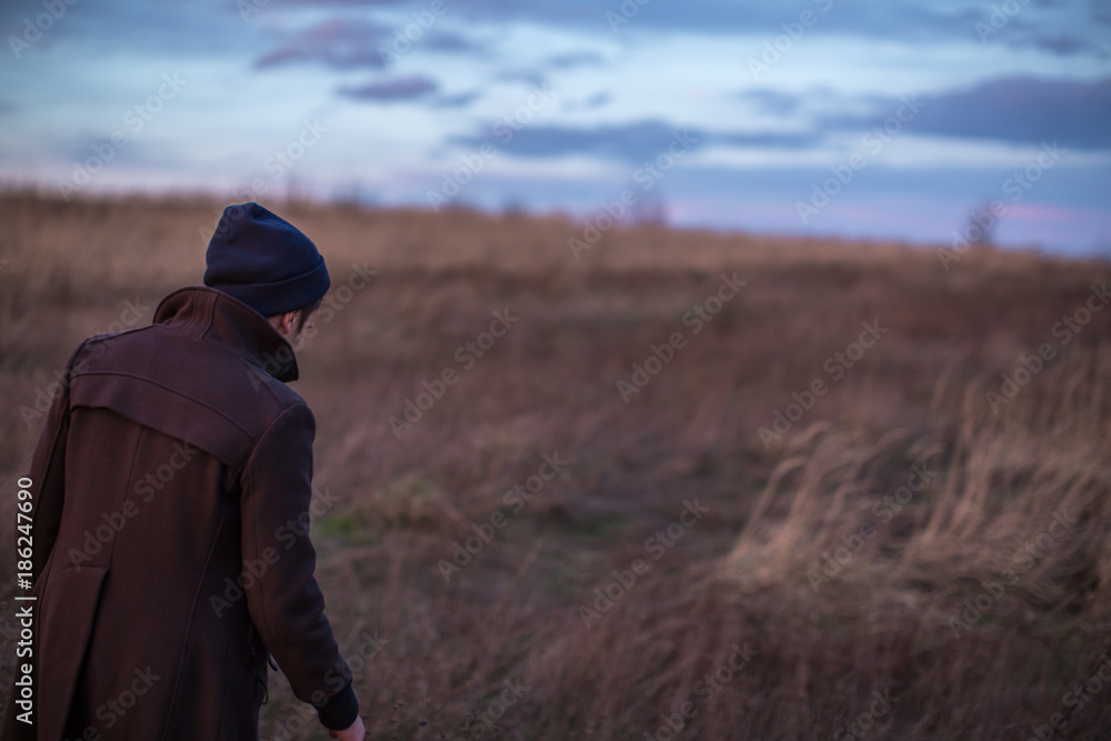 Man walking in the autumn field during sunset Man walking in the autumn field during sunset