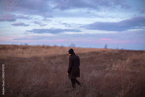 Man walking in the autumn field during sunset