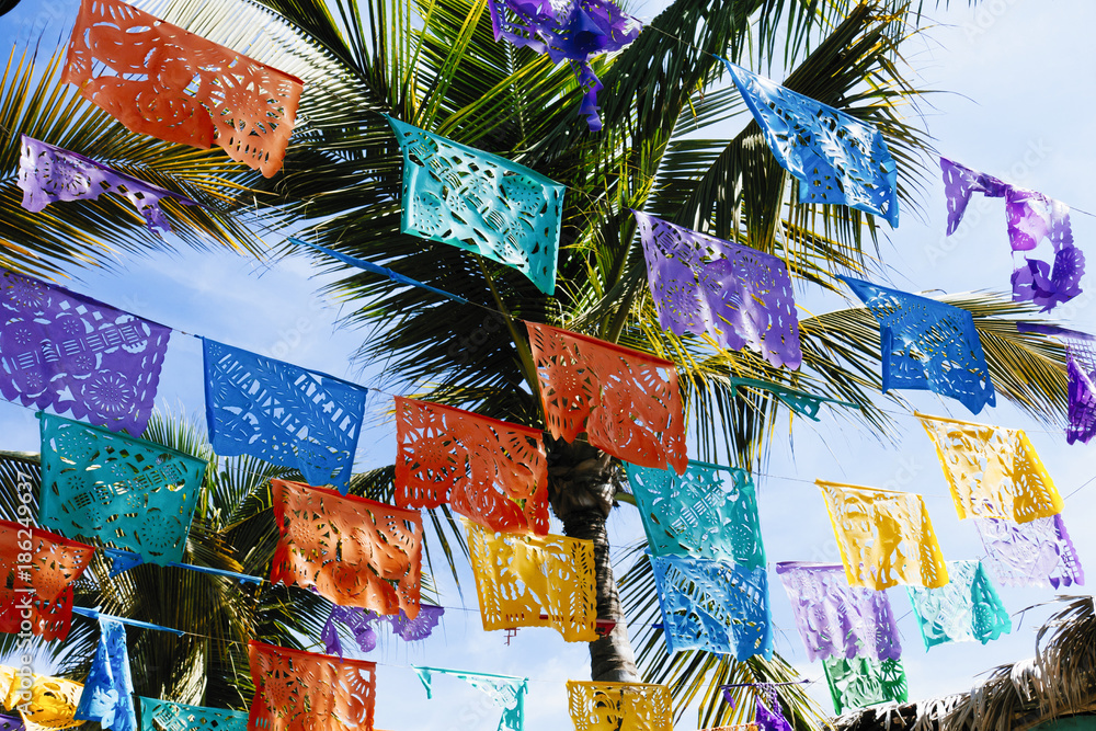 Colorful Mexican flag decorations hanging from palm trees Stock Photo