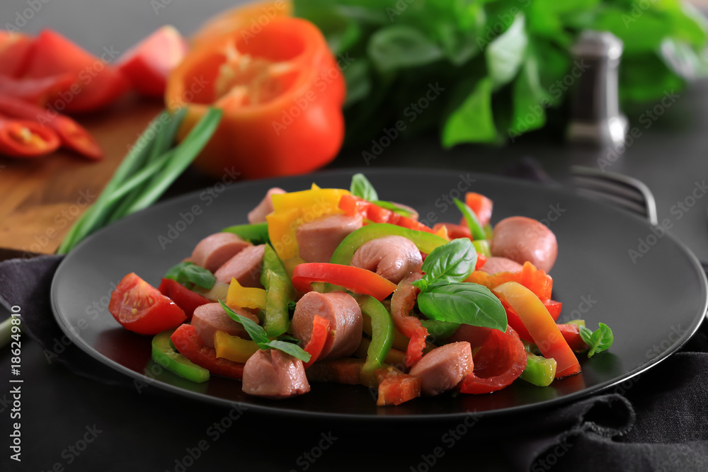 Plate with vegetable salad and sausage on table